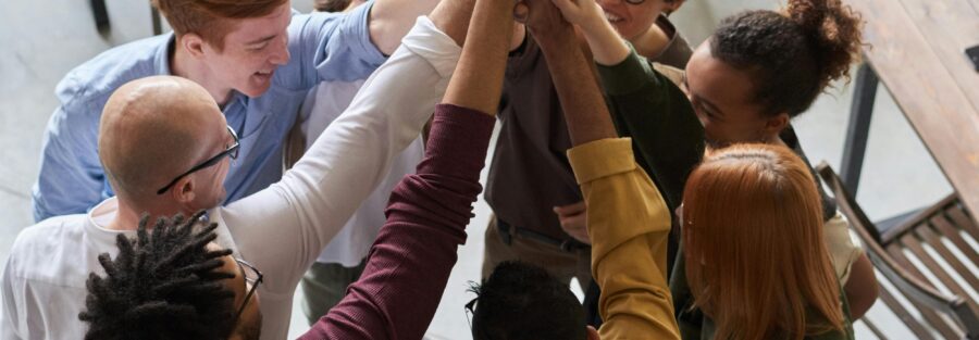 A diverse group of professionals high-fiving in a modern office, showcasing teamwork and collaboration.